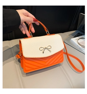Detail der orangefarbenen Stepptasche mit Tweed-Klappe und Metallbogen-Verzierung