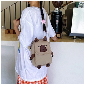 Detail view of a cute capybara shaped crossbody bag worn by a model in a cozy cafe