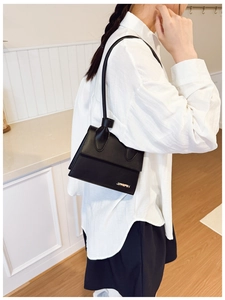 Gros plan d'un petit sac bandoulière noir minimaliste porté par un mannequin en intérieur