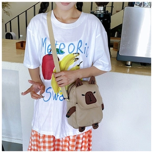Close-up of cute khaki capybara crossbody bag with adjustable strap in a cozy cafe setting