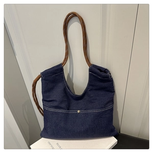 Detail of dark blue denim tote bag with white stitching and woven rope handle