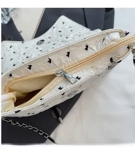 Detailed view of the smooth silver zipper and floral print on white shoulder bag