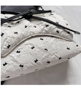 Detailed macro view of white pleated fabric with black bow print and leather strap