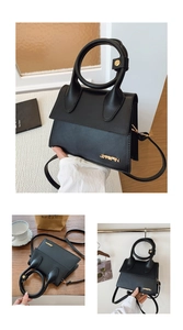 Detail of black leather handbag with large round handle and adjustable shoulder strap