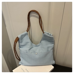 Detail of light blue denim tote bag with brown woven rope straps and silver snap button