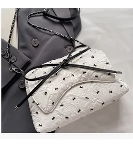 Detail of white seersucker baguette bag with black bow and metal chain strap