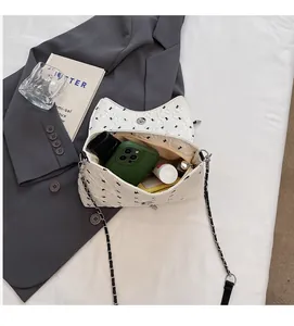 Interior view of white cat-ear chain bag showing space for phone and makeup