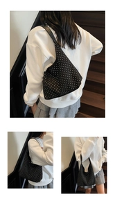 Detail view of black crescent underarm bag with white decorative polka dots and wide strap