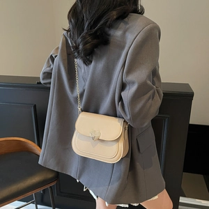 Elegant beige saddle shoulder bag with heart lock and gold chain strap for women