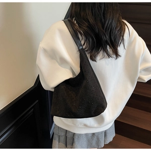 Detail of black suede hobo bag with small rhinestones worn on shoulder by model