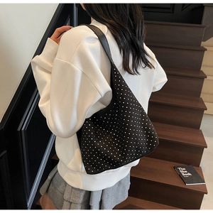 Detail of black sequined bucket bag with silver dots worn by a model in casual outfit