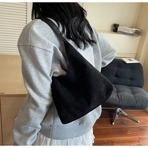 Detail of black suede crescent bag with metallic studs on a model's shoulder