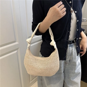 Beigefarbene Hobo-Tasche aus Stroh mit weißem Ledergriff und Knotendetails am Model