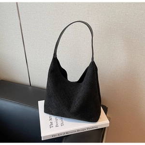 Detailed view of black suede hobo bag with sparkling rhinestones on a white book