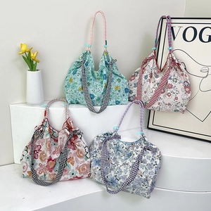 Floral canvas tote bags with checkered woven handles in pastel colors displayed on stands