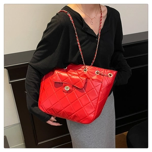 Détail du sac bandoulière rouge matelassé avec chaîne dorée et fermoir rotatif