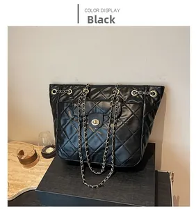 Détail du sac cabas matelassé noir avec fermoir tournant doré et bandoulière chaîne