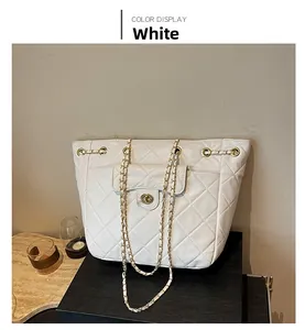 Détail du cabas matelassé blanc avec bandoulière chaîne dorée et fermoir rotatif