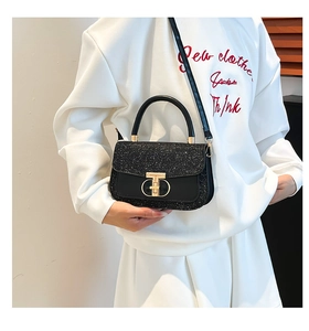 Detail of black crossbody bag featuring a glitter flap and iconic T-shaped metal clasp