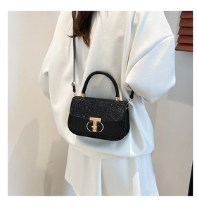 Close-up of black sequined flap bag with gold dual-ring lock on white dress background