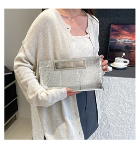 Detail of silver crocodile pattern clutch bag with metallic hollow handle for women
