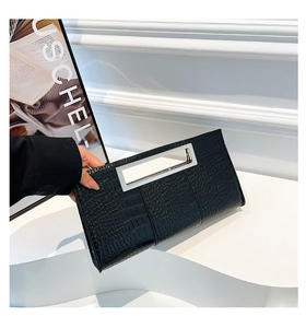 Detail of black faux crocodile skin texture and silver metal handle on envelope clutch