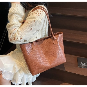 Gros plan d'un grand sac cabas tressé marron foncé avec une texture de cuir de luxe
