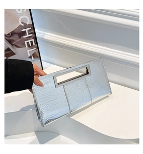 Detail of silver crocodile-patterned clutch with a sleek rectangular metal handle