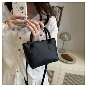 Close-up of black lychee texture leather bucket bag with elegant metal hardware and handles