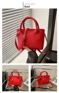 Detail der roten Eimertasche mit Lychee-Lederstruktur und goldenen Metallbeschlägen