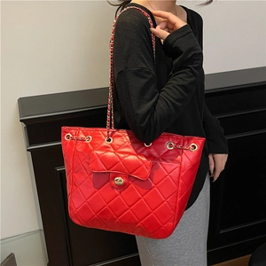 Sac fourre-tout rouge matelassé avec bandoulière chaîne dorée porté par un mannequin