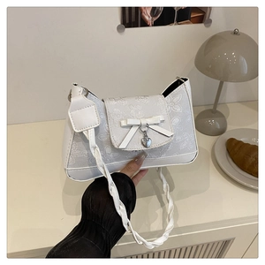 Detail der weißen bestickten Hobo-Tasche mit Herzanhänger und gewebtem Trageriemen