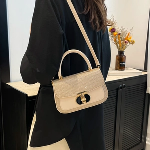 Chic beige sequined flap handbag with gold T-lock and long shoulder strap in home setting