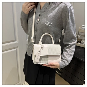 Detail view of white patchwork crossbody bag with textured weaving and fashion tag