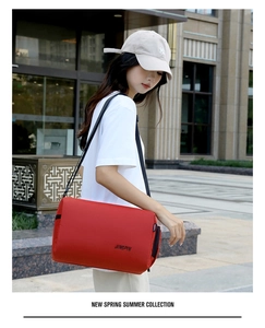 Rode nylon cilindervormige crossbodytas met JINGPIN-logo gedragen in een stadse setting
