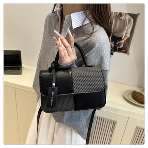 Détail d'un sac bandoulière bicolore noir et gris avec étiquette mode et texture tissée