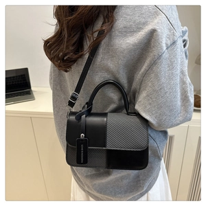 Détail d'un sac bandoulière bicolore avec cuir noir et texture tissée grise élégante