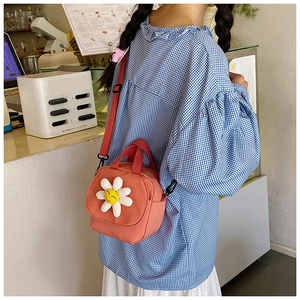 Detail of pink canvas mini crossbody bag featuring a 3D daisy and red woven strap