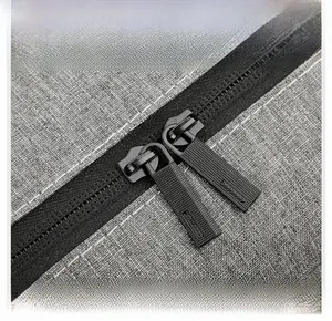 Detailopname van duurzame metalen tweewegritsen op een grijze tas van oxford-stof