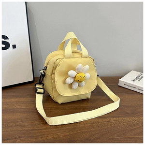 Detail of yellow canvas bag featuring a 3D daisy smiley face on a wooden desk