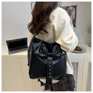 Detailed view of black faux leather tote featuring a large rhinestone bow decoration