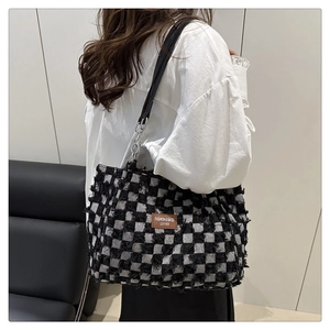 Close-up of black and white checkered tote bag with fringe edges and leather logo patch