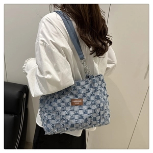 Detail of blue checkerboard tote bag with fringe texture and leather chain strap