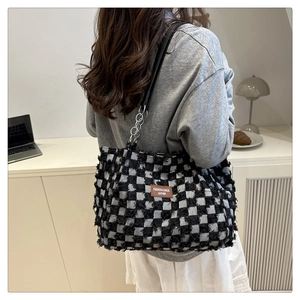 Detailed view of large checkered tote bag with tweed texture and chain strap on shoulder