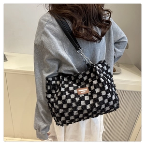 Close-up of black and white checkerboard tote bag with frayed fringe edges and leather tag