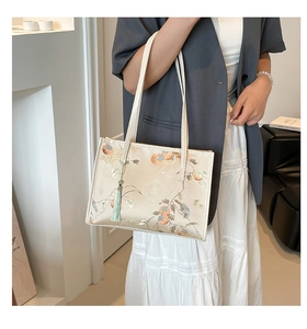Detail of cream silk tote with traditional persimmon embroidery and green tassel