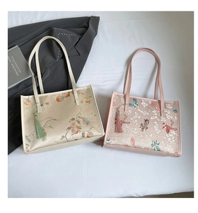 Detailed close-up of Chinese embroidery patterns on silk tote bags with beaded tassels