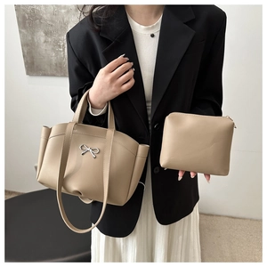 Detail of khaki bucket bag with silver bow accent and matching zip pouch set