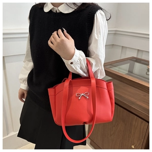 Détail du sac seau rouge avec nœud en métal argenté et bandoulières polyvalentes