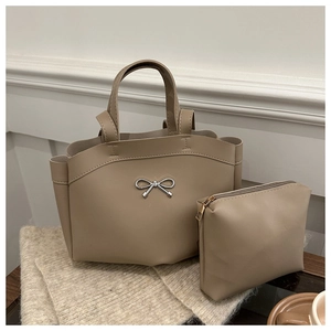 Detail of beige bucket bag with silver metal bow and matching zipper pouch in soft PU leather